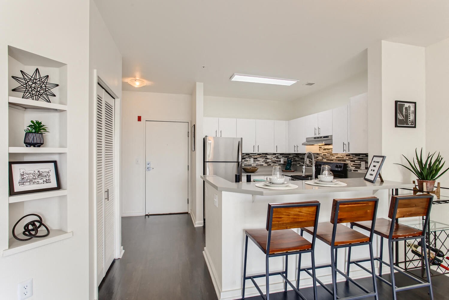 Downtown Portland OR Pet-Friendly Apartments - Linc 245 - Modern Kitchen with Stainless Steel Appliances, a Breakfast Bar with Wooden Stools, Colorful Tile Backsplash, and White Cabinets